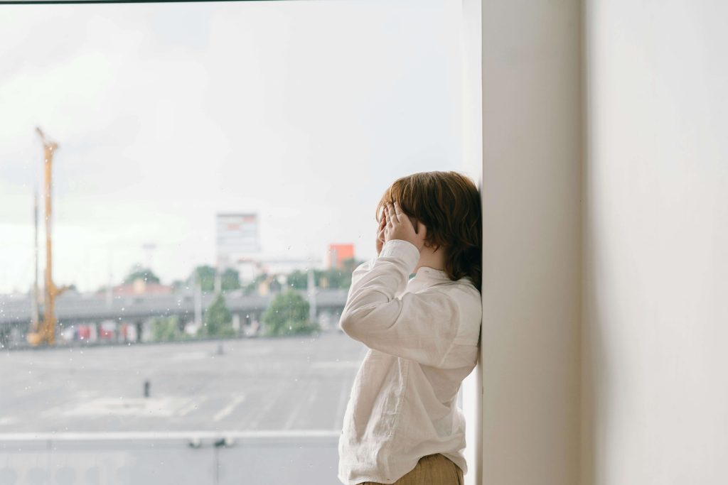 Child with anxiety standing by a window. Tips for Helping children work through their anxiety. Brain Insights.