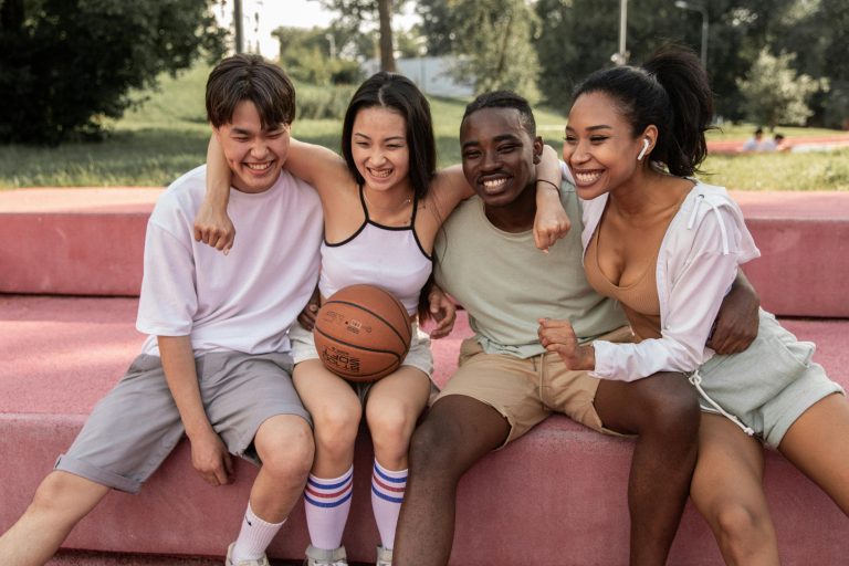 Group of teen friends hanging out in a basketball court.